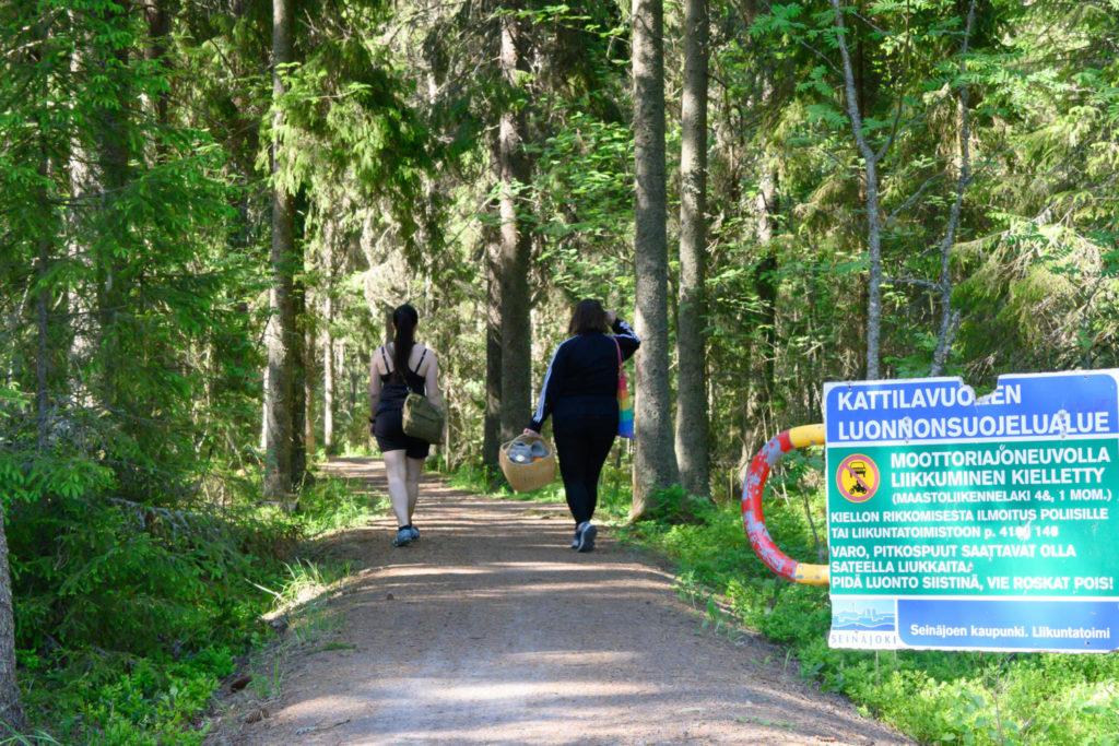 Ystävykset kävelemässä Kattilanvuoren luontoreitillä eväskorin kera