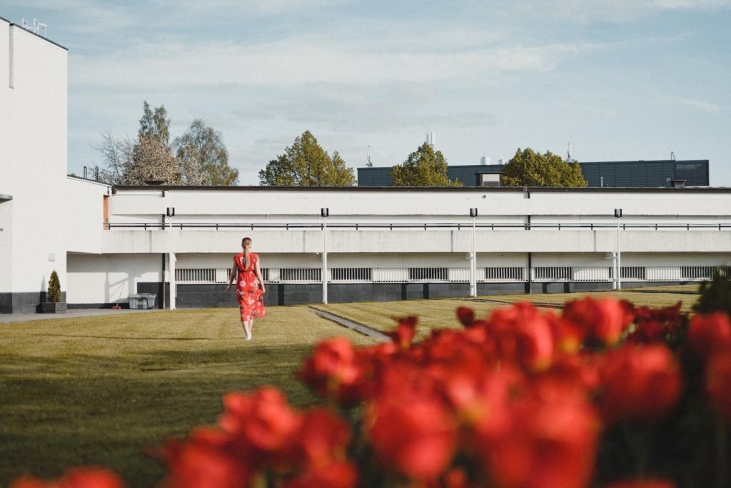 Nainen kävelee punainen mekko päällän Lakeuden Ristin kirkon pihamaalla