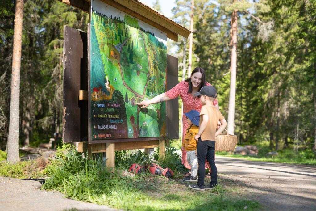 Äiti esittelee lapsilleen lastenreitin opastetta ja kertoo minne ollaan menossa.