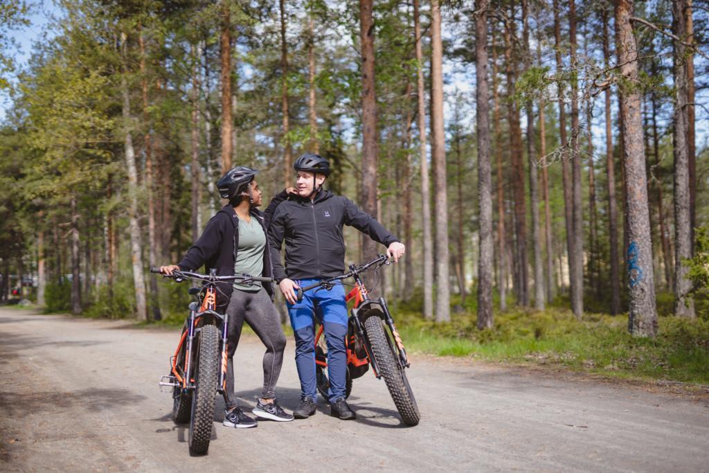 Pariskunta taluttavat fatbikepyöriä luontoreitillä.