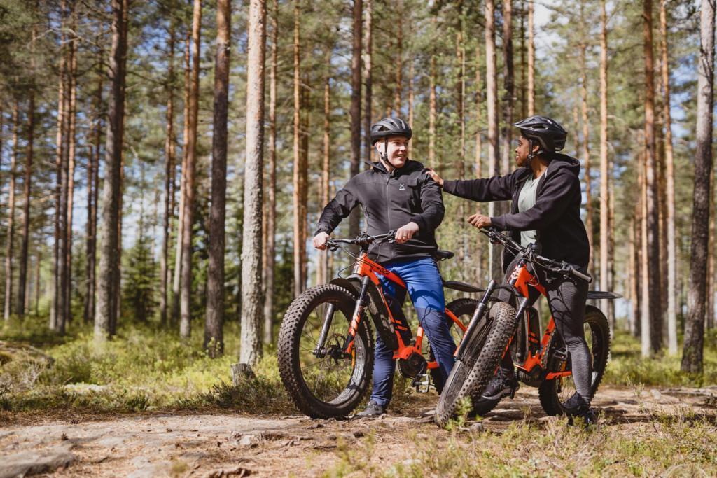 Pariskunta pitää taukoa ja keskustelee metsän reunassa.