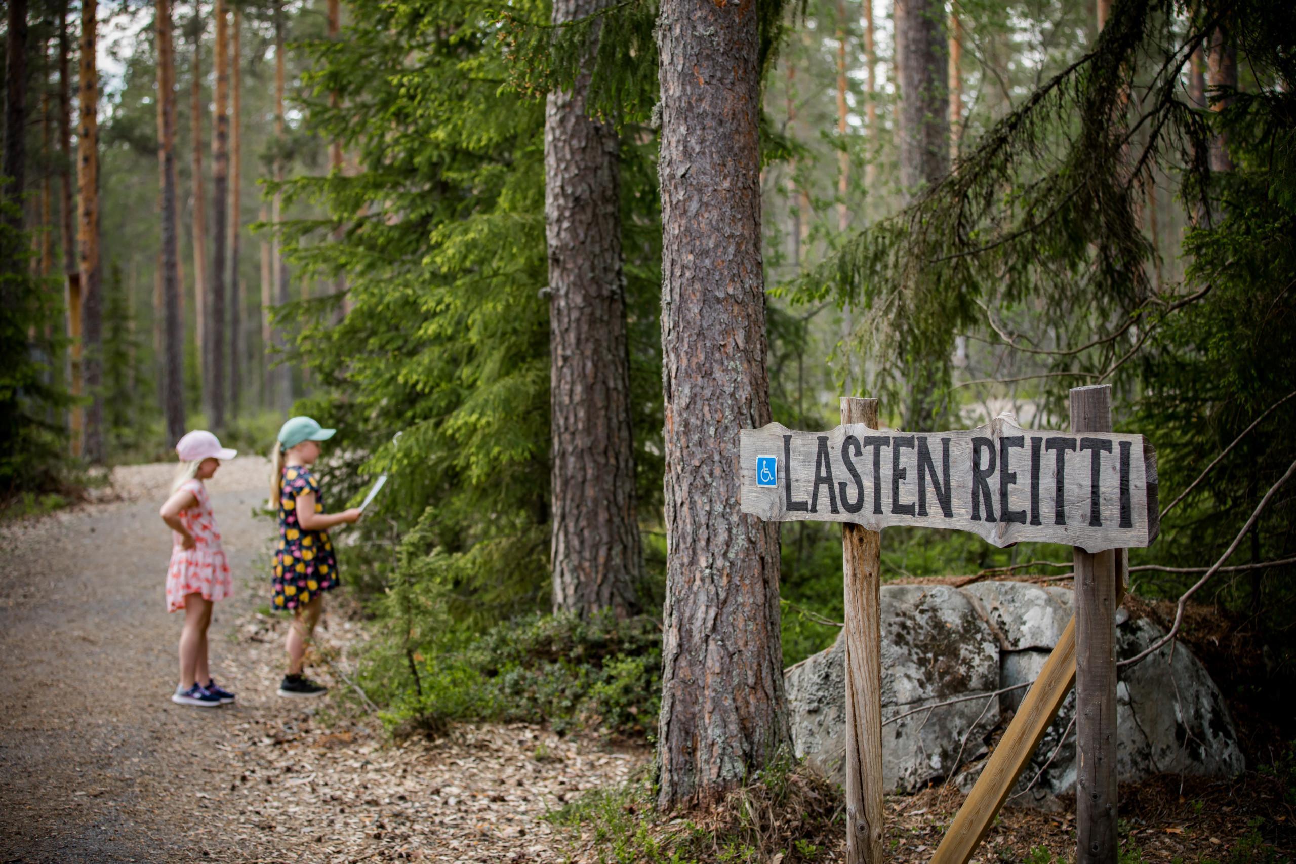 Lapset lastenreitin polulla kävelemässä kohti metsikköä