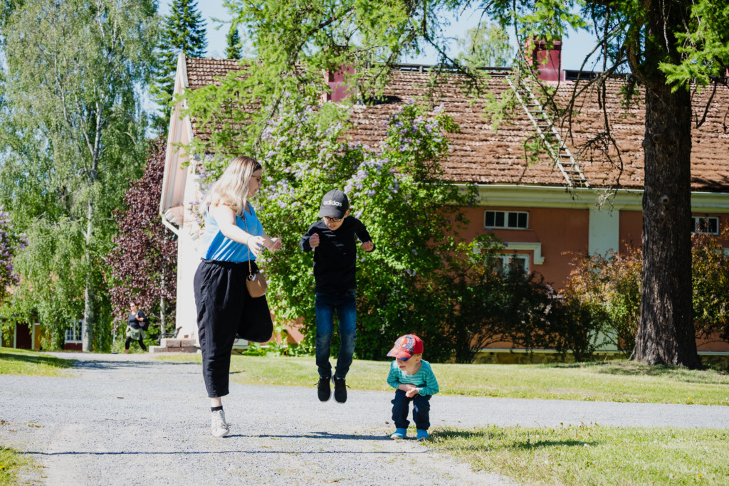 Äiti ja kaksi poikaa hyppelehtimässä Törnävän kartanon pihapiirissä