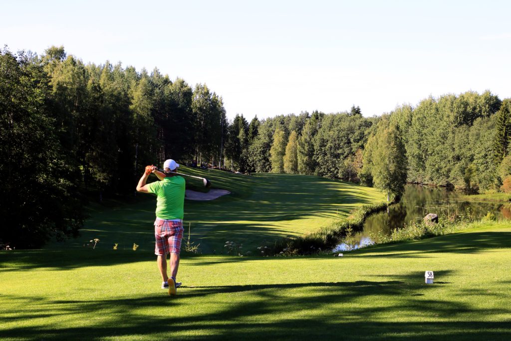 Golfaaja lyö pallon joen yli sijaitsevalle viherilllä Ruuhikoski Golfilla