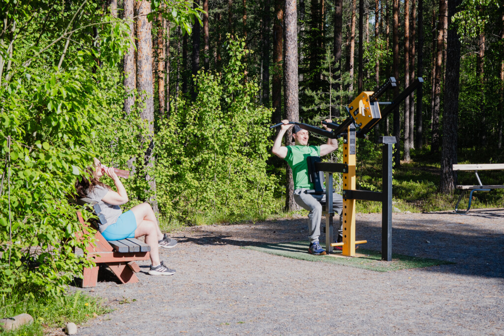 Nainen ja mies ulkokuntosalilla metsän vieressä