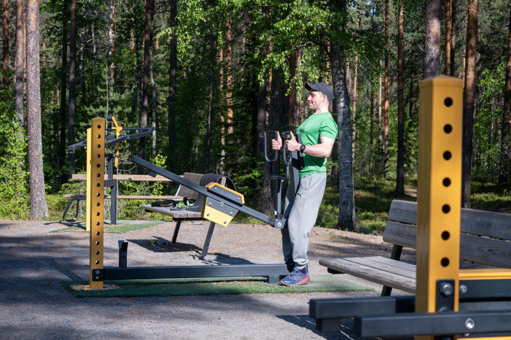 Mies nostelee painoja ulkoliikuntapaikan laitteessa