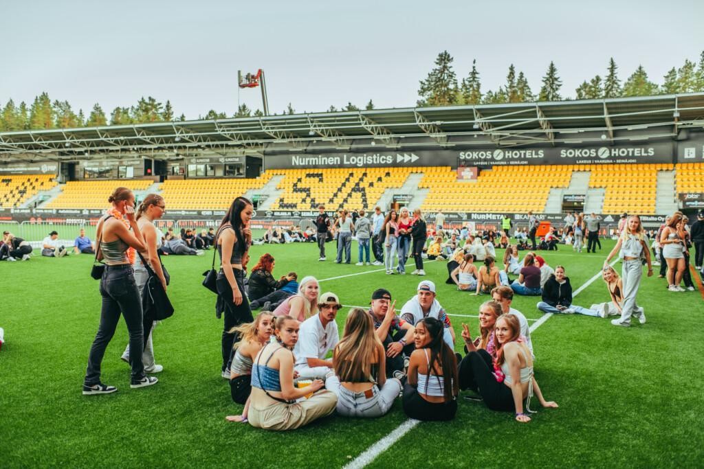 Nuoria ihmisiä istumassa festivaalialueella