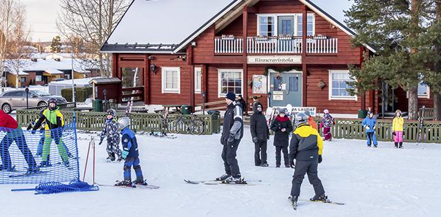 Laskettelijat Joupiskan laskettelukeskuksen edustalla alarinteessä.